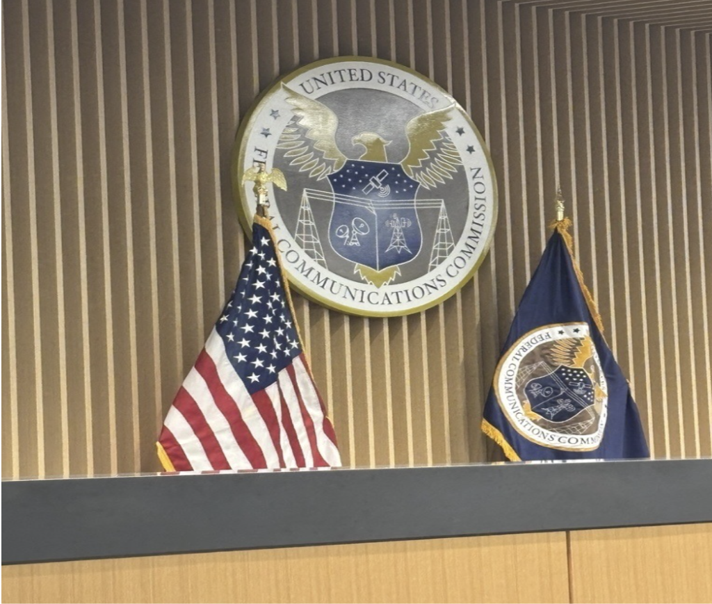 Federal Communications Commission seal displayed above the United States and FCC flags at FCC headquarters in Washington, DC